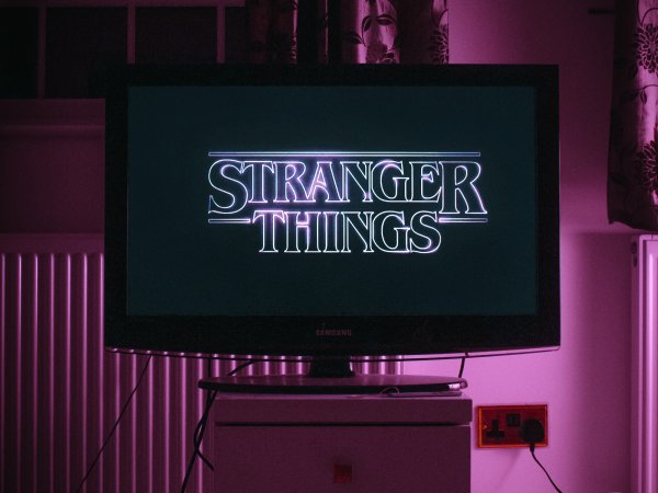 A TV with the Stranger Things title screen on it, in a dark room bathed in purple light. Exactly what you might see if you're binge-watching instead of going to sleep.