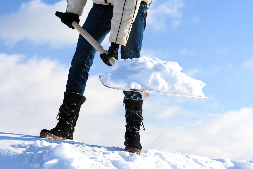 Person shoveling snow, angle from the ground looking up.