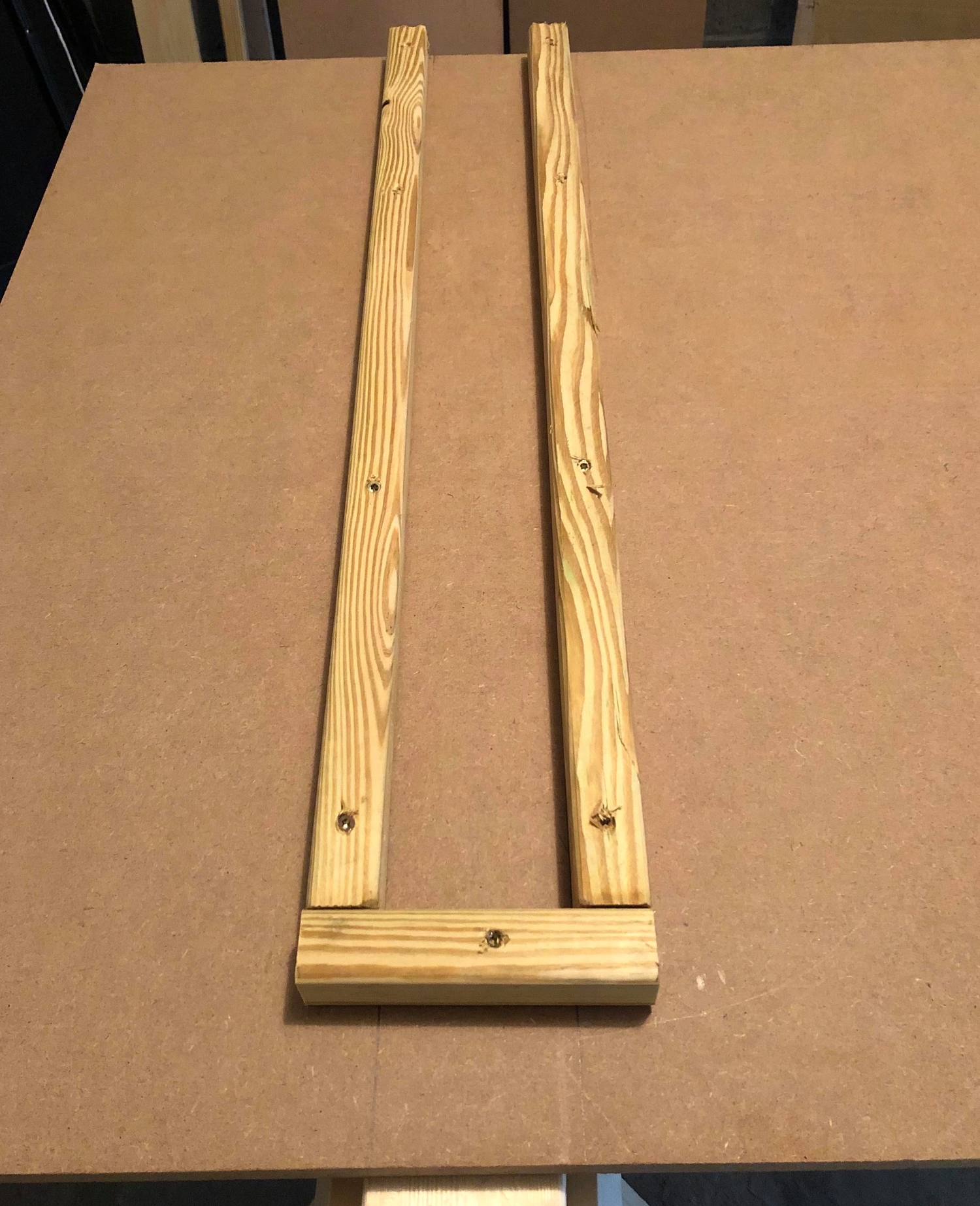 pieces of 1-by-1 wood screwed to an MDF sheet to serve as brackets for saw horses to fit into