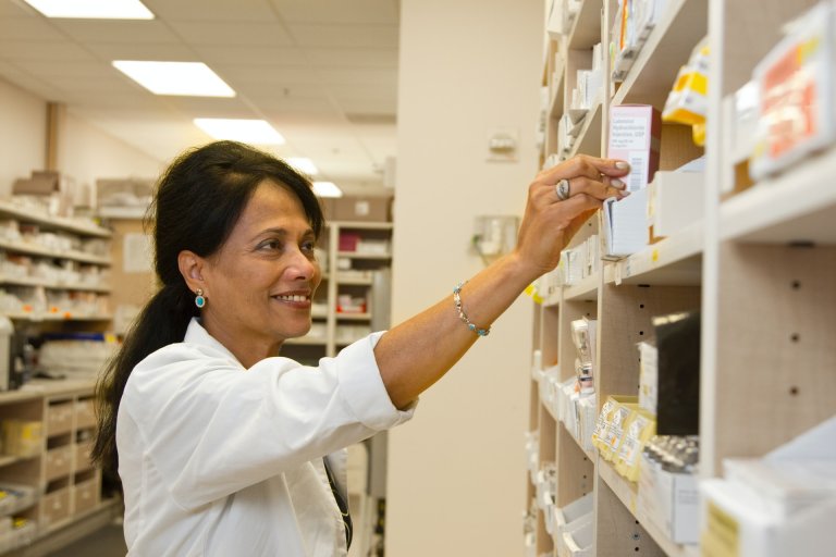 A pharmacist picking a medication off a shelf