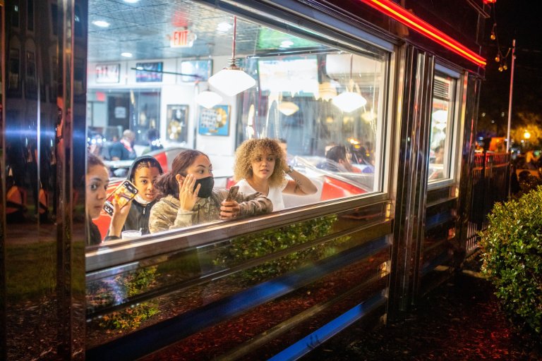 People wearing masks looking out the window of a diner during the COVID-19 pandemic