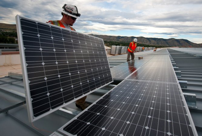 Construction workers install solar panles.