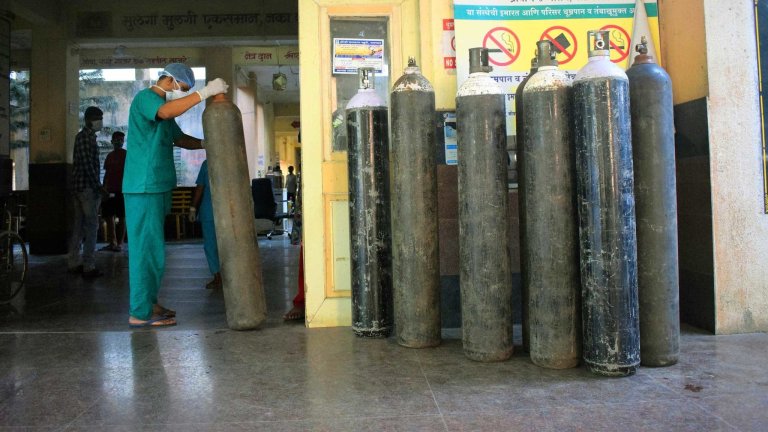 Medical worker in scrubs moving oxygen canister in Palghar, India
