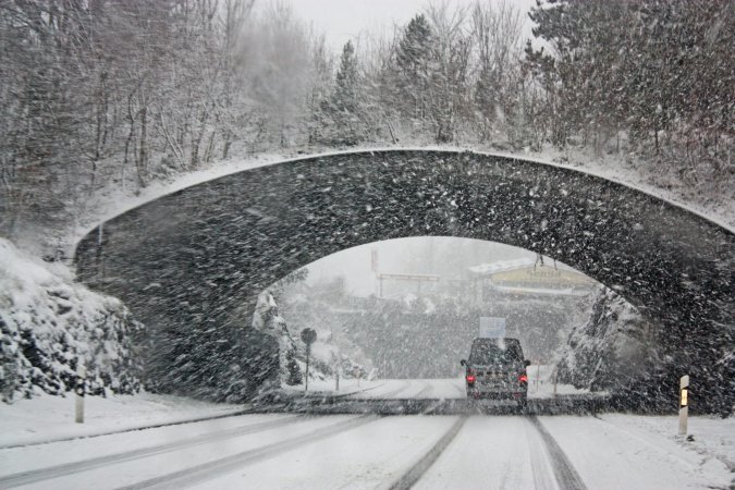 Truck driving under bridge in a blizzard.
