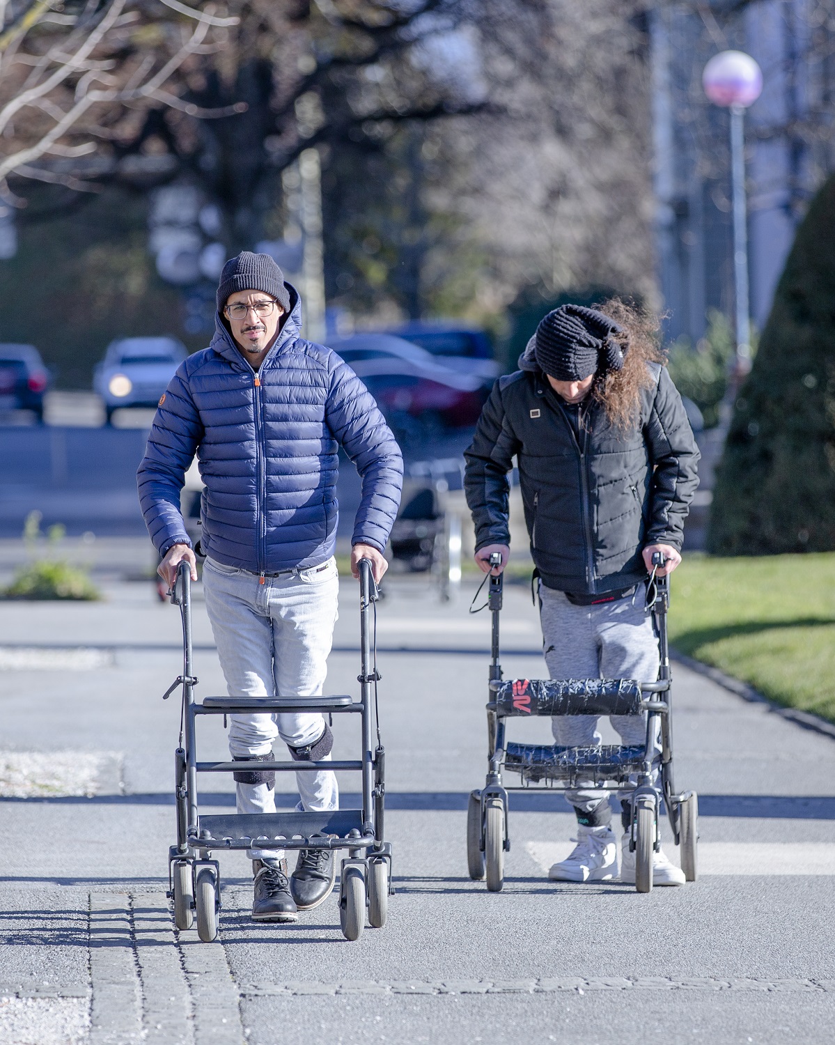 Two patients with paralysis walking down a sidewalk with aides after electrode therapy