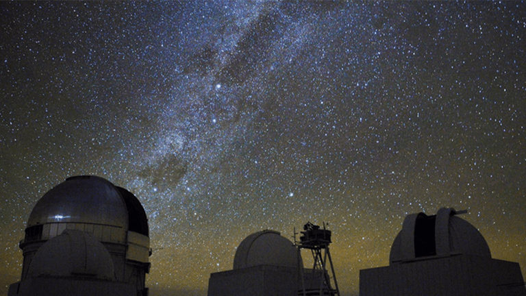Two giant, circular ground telescopes with an overlay of a starry night sky.