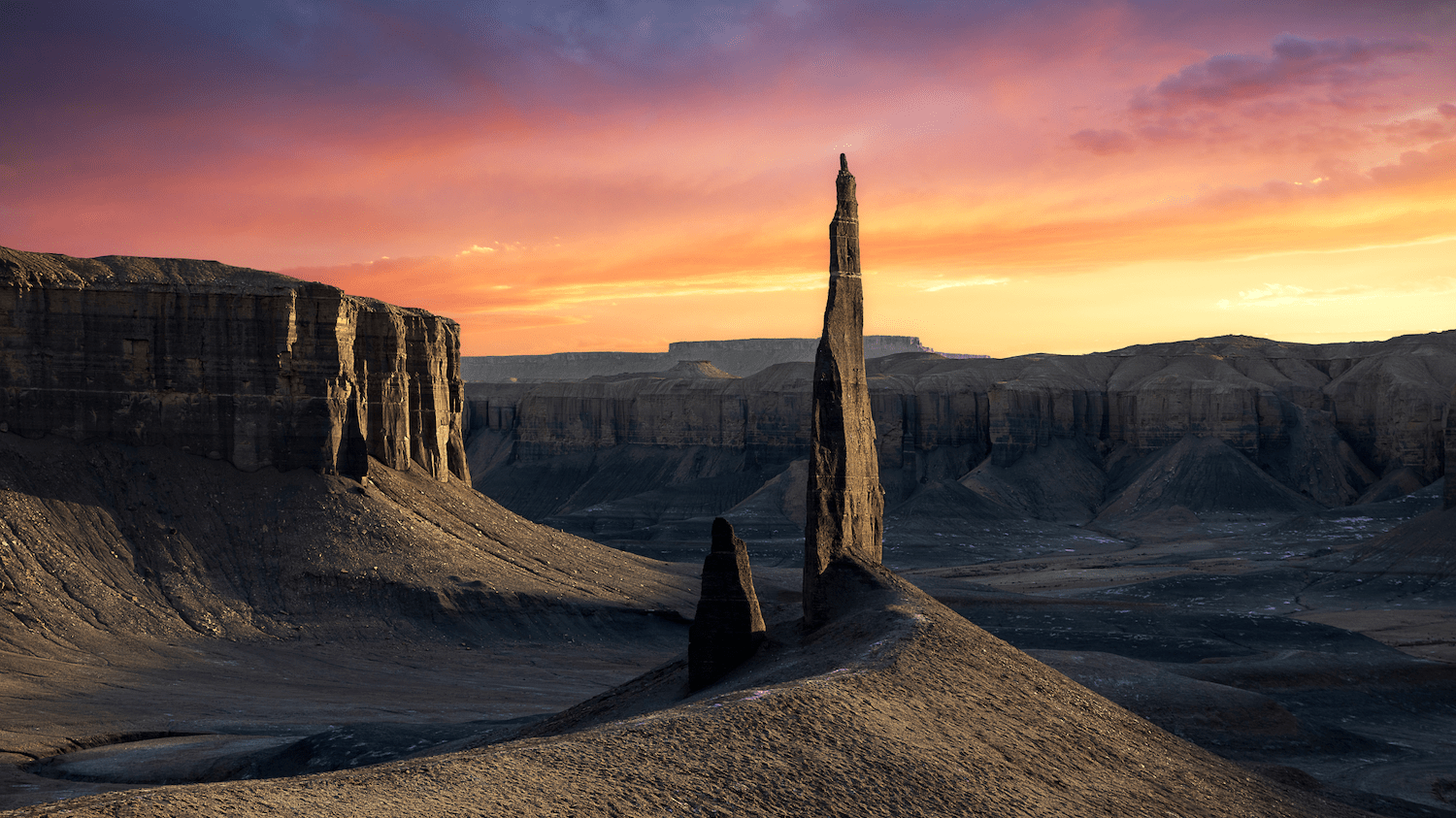 a rock juts out under the pink sky during sunset