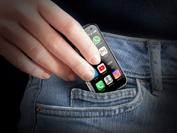 A person putting a small phone in their pocket.