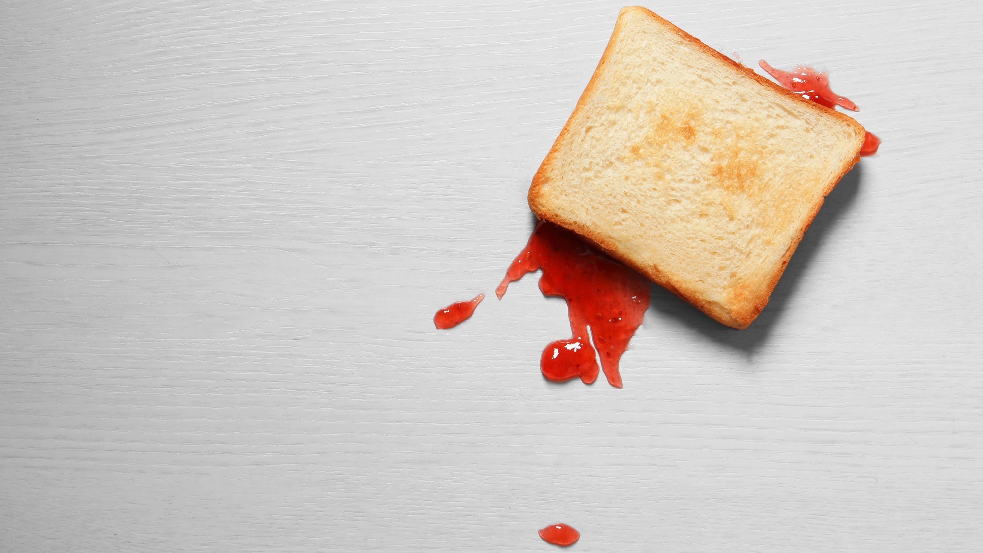 a slice of jelly toast faced down on the floor