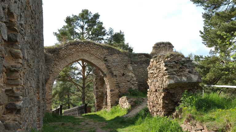 the stone remains of a castle, revealing an archway, wall, and a tower