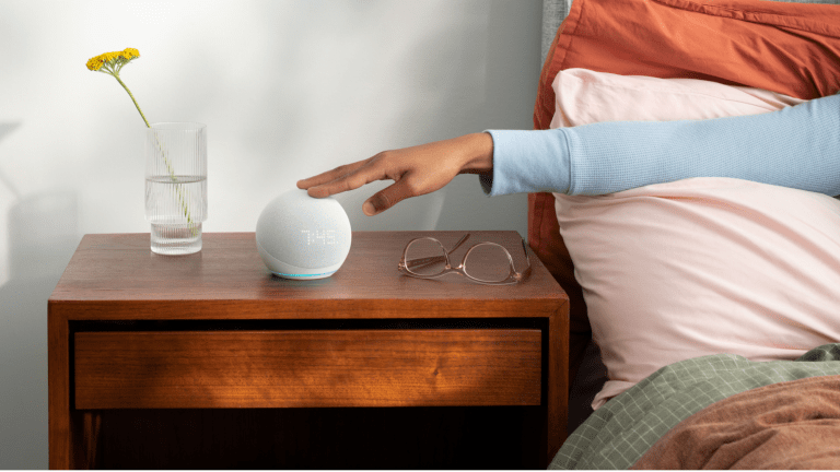 Woman's hand reaching out from bed to turn off alarm on Amazon Echo Dot