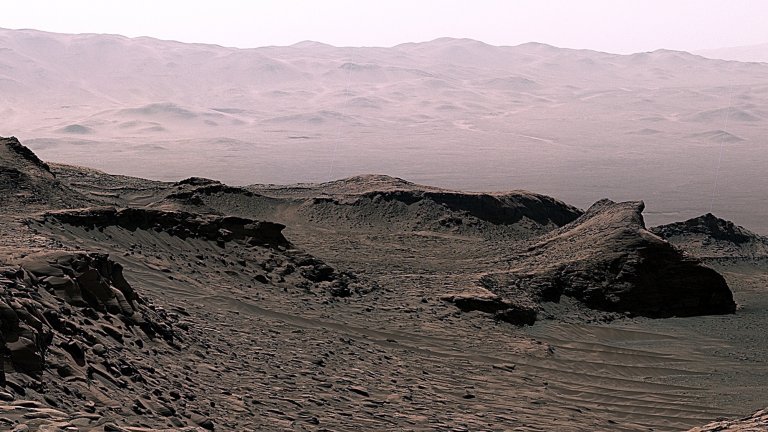 A photomosaic taken by the Curiosity Rover on April 30, 2023 at the Ubajara drill site in Gale Crater, Mars. Rock powder samples drilled here contained substantial amounts of siderite (an iron carbonate mineral). The siderite played a role in ancient carbon cycling processes that impacted conditions at the planet’s surface. Rover tracks in the foreground are 40 cm wide. (Credit: NASA/JPL-Caltech/MSSS)