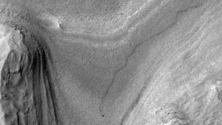 Black and white overhead shot of Mars rover and tracks on planet