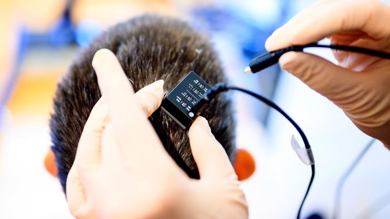 a device on the top of the head with hands holding it