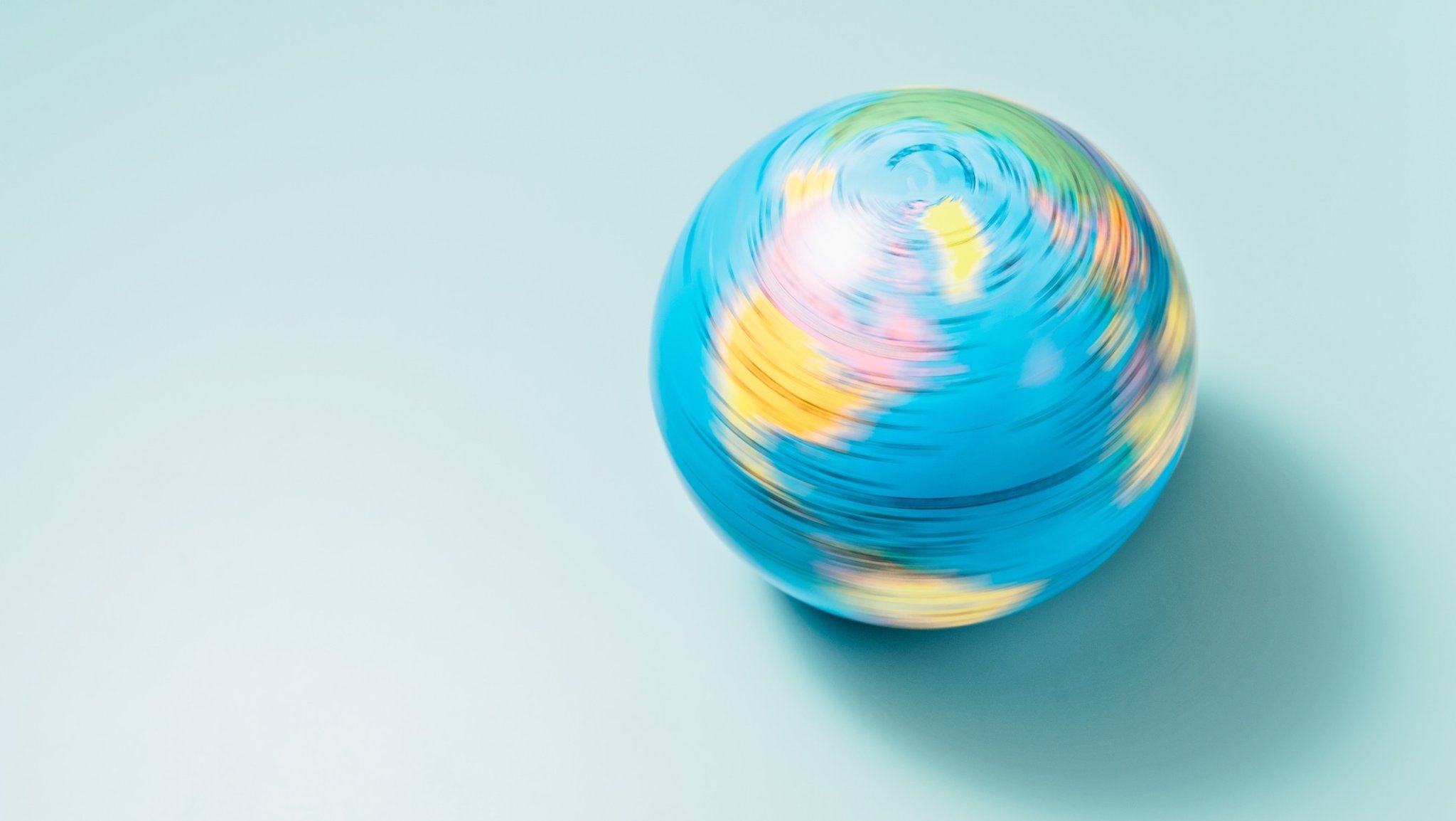 Blue Colored Motion Blurred Earth Globe Spinning on Light Blue Background.